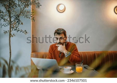 Handsome man in smart casual sitting in the cafe and working remotely.