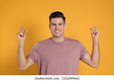Handsome man snapping fingers on yellow background