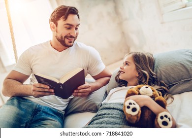 Handsome man is spending time with his little cute daughter. Reading fairytales while daughter is lying in bed and ready to sleep. - Powered by Shutterstock