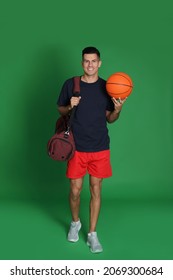 Handsome Man With Sports Bag And Basketball Ball On Green Background