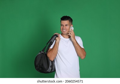 Handsome Man With Sports Bag And Smartphone On Green Background