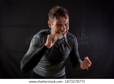Handsome man in sportswear is insanely rejoicing at the received silver medal in the studio on a black background