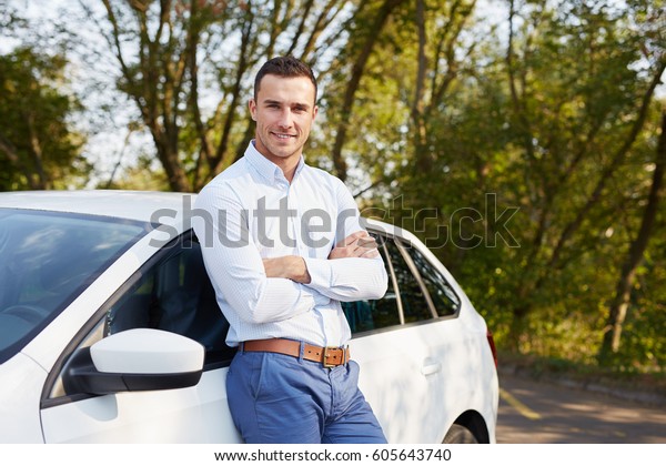 Handsome man standing in\
front of car