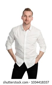 Handsome man standing in front of a white background wearing a white shirt and black jeans looking at camera.