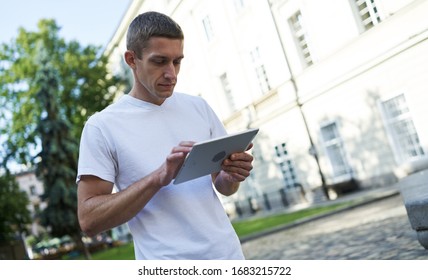 handsome man standing in the street looking for something on his tablet - Shutterstock ID 1683215722