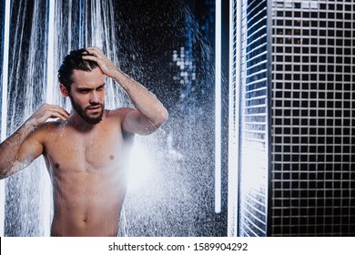 handsome man with strong muscles, perfect body stand under running water taking shower