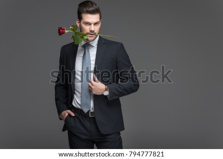 handsome man in suit holding red rose in mouth, isolated on grey Stock photo © 