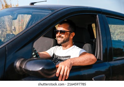 Handsome Man with sunglasses driving a car on his road trip on sunny day - Shutterstock ID 2164597785
