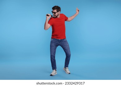 Handsome man with sunglasses and microphone singing on light blue background - Powered by Shutterstock