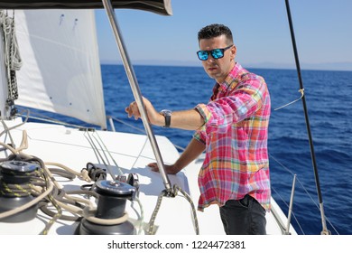 Handsome man in sunglasses stands on yacht in blue sea at sunny summer day - Powered by Shutterstock