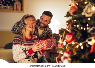 Handsome Man Surprising A Girl With A Christmas Present.