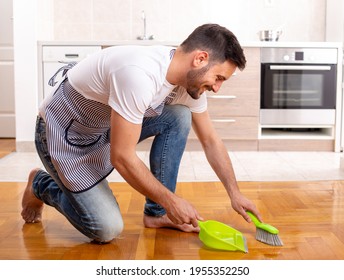 Handsome man sweeping floor with dust pan in front of kitchen cabinets at home - Powered by Shutterstock