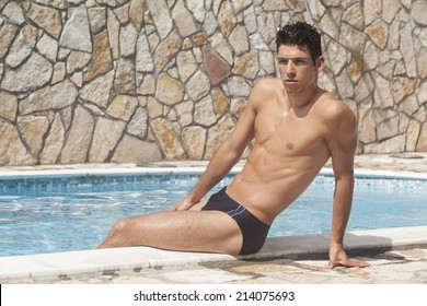 Handsome man in swim briefs by the pool