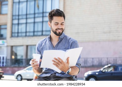 Handsome Man With Takeaway Cup  Reading Blank Book Outdoors