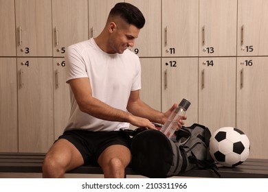 Handsome man taking bottle from sports bag in locker room - Powered by Shutterstock