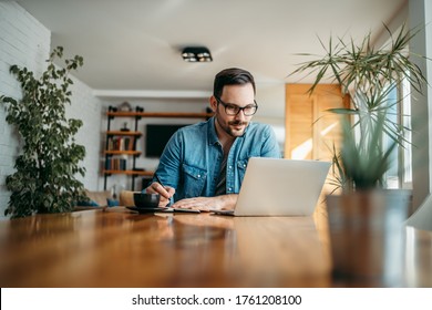Handsome Man Taking Notes And Looking At Laptop, At Home Office, Portrait.