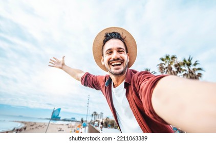 Handsome man taking selfie in Barcelona city, Spain - Happy tourist having fun walking outside on summer vacation - Travel, holidays and European landmarks concept - Shutterstock ID 2211063389