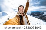 Handsome man taking selfie on top of snowy mountain - Young hiker walking outside in white forest - Sport, technology and winter activities concept