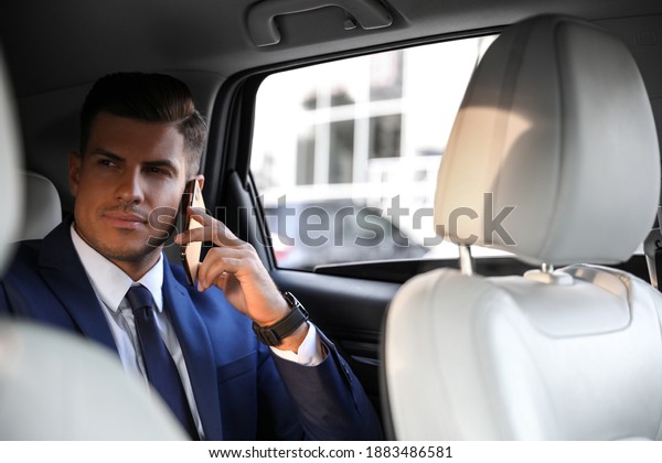 Handsome man talking\
on phone in modern car