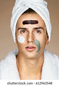 Handsome man with three different face masks (chocolate, cream and clay masks). Photo of man with perfect skin. Grooming himself
