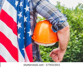 Handsome man with tools, holding an American Flag. View from the back, close-up. Concept of work and employment - Shutterstock ID 1776513311