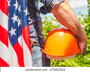 Handsome man with tools, holding an American Flag. View from the back, close-up. Concept of work and employment - Shutterstock ID 1776513314