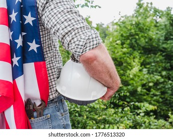 Handsome man with tools, holding an American Flag. View from the back, close-up. Concept of work and employment - Shutterstock ID 1776513320