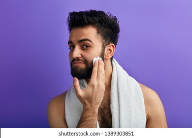 A Handsome Man With A Towel Around His Neck Applies , Puts Shaving Foam On His Face Before Shaving. Close Up Photo. Skin Care