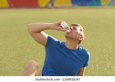 Handsome man trains at a stadium in Moscow city. He put on sports uniform to play football outdoors. in sunny summer day. Concept of the active lifestyle. He drinking water. Frontal view. Close up - Powered by Shutterstock
