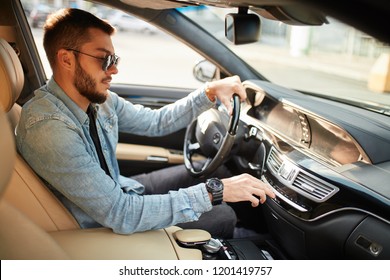 Handsome Man Turning On Stereo System While Driving A Car. Close Up Side View Photo. Male Turning On The Radio