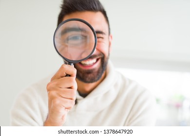 Handsome man using magnifying glass, doing funny faces