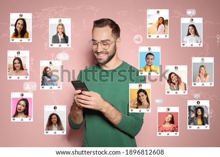 Handsome man visiting online dating site via smartphone on pink background