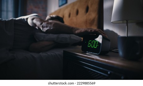 Handsome Man Wakes Up and Turns off Alarm Clock. Proceeds to Have a Productive Day of Work. Stylish Apartment. Focus on the Clock Showing Six O'Clock. Bedroom Apartment