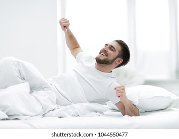 Handsome Man Waking Up In A Cosy Bedroom.