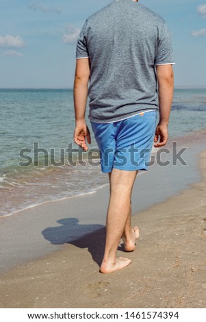 Handsome man walking alone on the beach with bare feet. Rest by the beach.