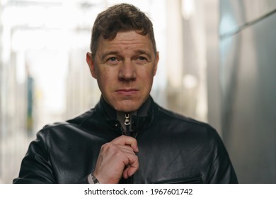 Handsome man walking at city street. He catches the lock on the leather jacket. He is ready to walk. Nothing scares him. He is ready for any challenge. He put on black leather jacket. Lifestle concept - Powered by Shutterstock