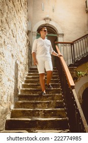 Handsome man walking down the old stone staircase at sunny day