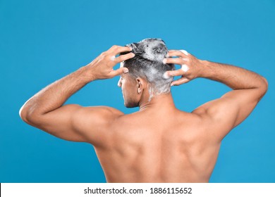 Handsome Man Washing Hair On Light Blue Background, Back View