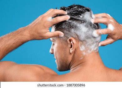 Handsome Man Washing Hair On Light Blue Background, Back View