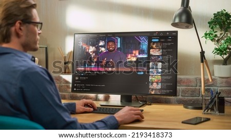 Handsome Man Watching Video Sharing Service Mock-up Where African American Influencer Talks About Lifestyle. Celebrity Blogger Having fun. Interface with Related Streams, Likes, Comments.
