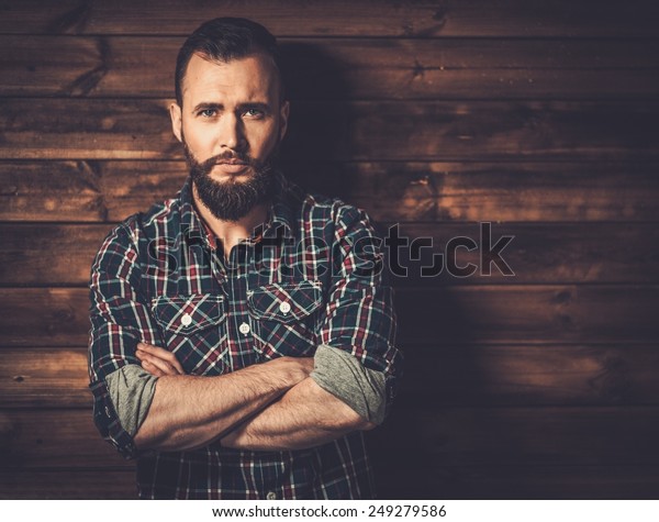 Handsome man wearing checkered  shirt in wooden rural\
house interior 