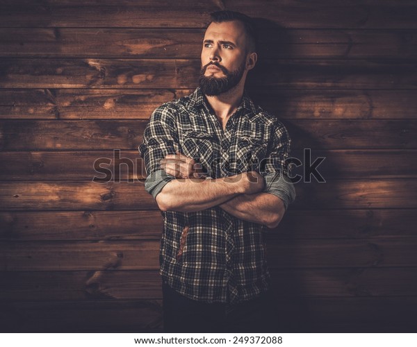 Handsome man wearing checkered  shirt in wooden rural\
house interior 