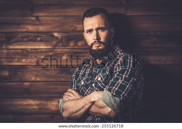 Handsome man wearing checkered  shirt in wooden rural
house interior 