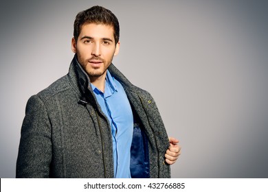 Handsome Man Wearing Jeans Clothes And A Coat Posing At Studio. Men's Beauty, Seasonal Fashion. Studio Shot.