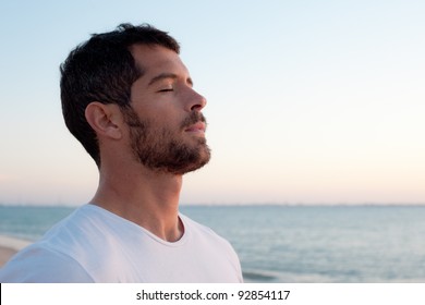 Handsome Man Wearing White Deep Breathing In Front Of The Ocean.