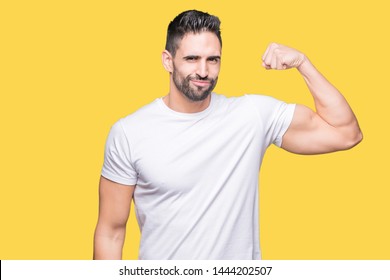 Handsome man wearing white t-shirt over yellow isolated background Strong person showing arm muscle, confident and proud of power