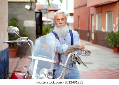 Handsome Man With White Beard Posing Near Motor Bike On The City Street, Looking At Camera.
                    