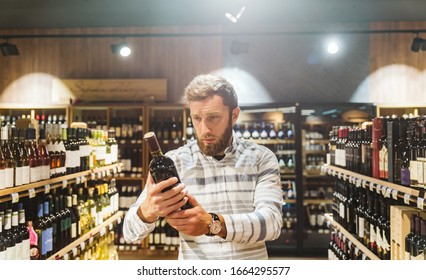 Handsome Man At A Wine Store Reading The Label On Bottle