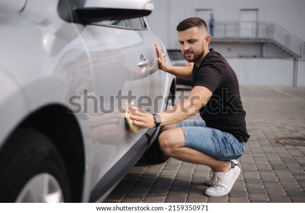Handsome man
wipes a car with a rag in a showroom at a self-service car wash.
Gray car. Polished car with hard
wax