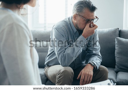 Handsome man wipes his tears while talking to the therapist
